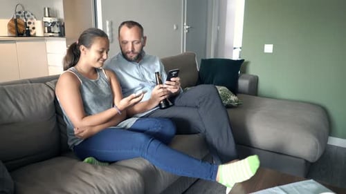 Teenage girl and man sitting on couch with phones