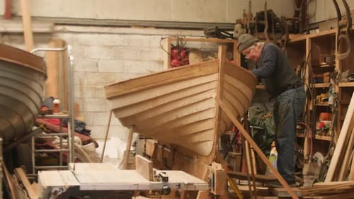 Construtor de barcos trabalhando em bote de lapstrake com tábuas de pinho, punt