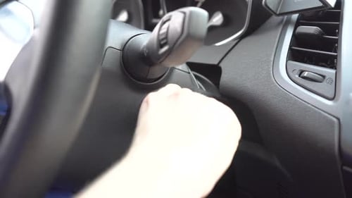Die Hand einer Frau steckte den Schlüssel in die Zündung und ließ ihn dort liegen
