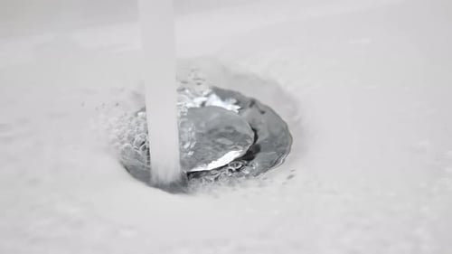 A água flui para baixo no orifício de drenagem da pia