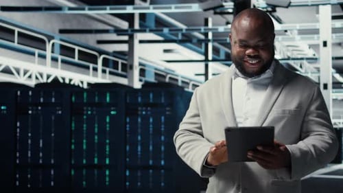 Close Up of Technician Walking in Data Center Using Tablet to Check Equipment