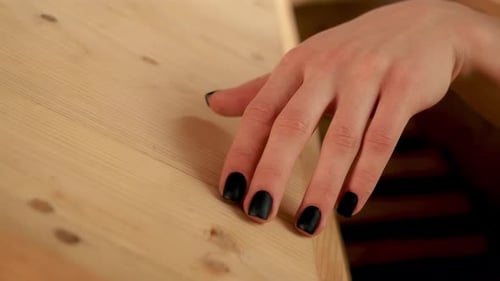 Hand of Young Girl with Beautiful Black Manicure Gently Runs Over Wooden Texture in Spa Enjoying