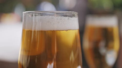 Celebration Beer Cheers Concept, Nahaufnahme von Händen, die Gläser eines Bieres hochhalten, von einer Gruppe im Freien