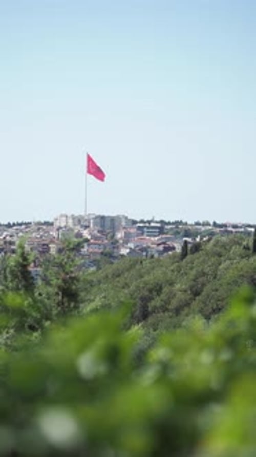 Cityscape with Red Flag Waving on Bright Day