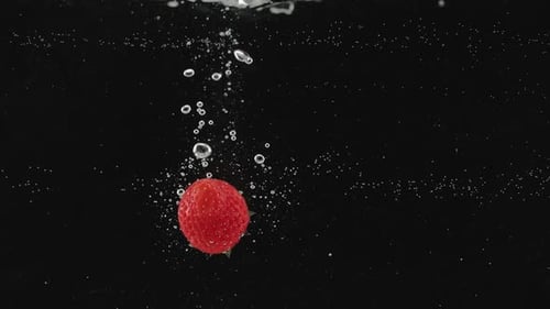 Strawberry Splashing Into Water Against a Black Background