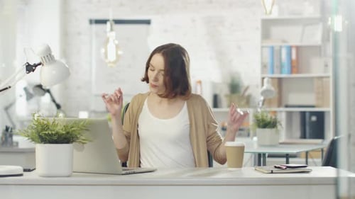 Young Woman Dancing at Desk in Office