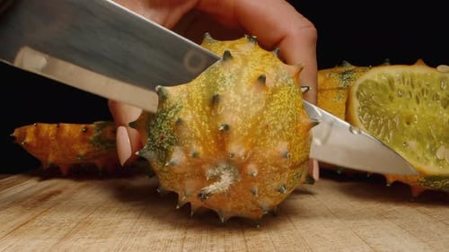 La caméra s'approche alors que le Kiwano épineux est découpé en deux. Un concombre africain sur la table