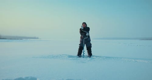 Fischer bohrt vereiste Oberfläche eines Flusses oder Sees zum Eisfischen im Winter Full-length Prores