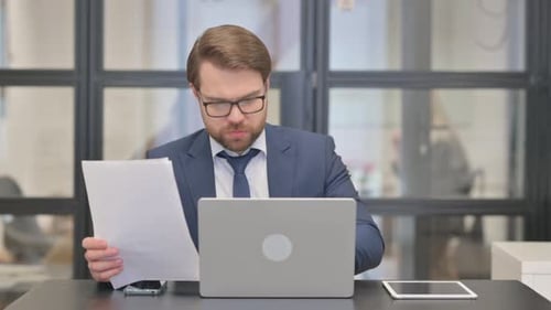 Bearded Man Working with Laptop and Documents
