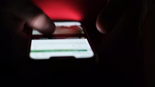 Hand Scrolling Through Content on Phone at Night