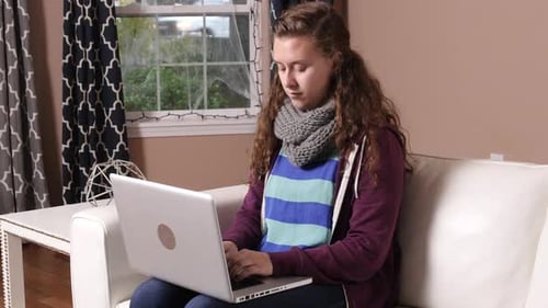 Teenage girl using laptop on a white couch