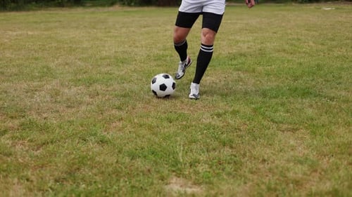 Vigorous Man Running Across Green Field While Skillful Maneuvering Soccer Ball