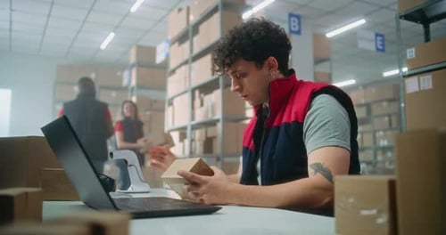 Parcel Processing Specialist Scans Package Prepares for Shipping to Customer Works on Laptop