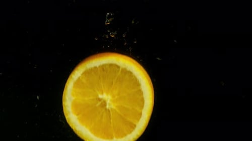 Orange Slice Falling Into Water on Black