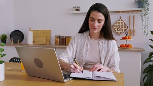 Woman Working at Home with Laptop and Notebook