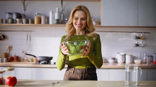 Woman Smiles Holding Healthy Salad in Bright Kitchen