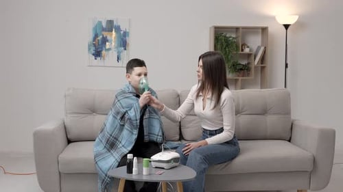 Boy with nebulizer and woman in living room