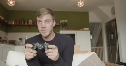 Young Man Plays Video Game at Home on Couch