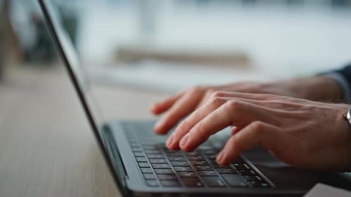 Бизнесмен вручную печатает клавиатуру ноутбука на современном офисном рабочем месте крупным планом