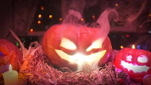Halloween-Dekorationen mit rauchenden Kürbissen im roten Licht, die auf trockenen Blättern in der Nähe liegen