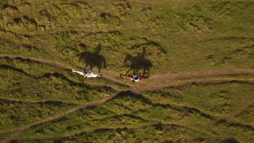 People Riding Horses Across Green Rural Field Aerial