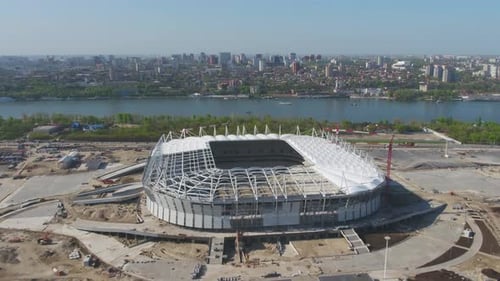 A Stunning Aerial View of a Modern Stadium Situated Adjacent to a Beautiful Water Body