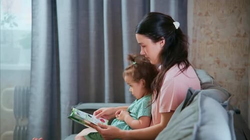 Mother and Child Reading a Book on Couch
