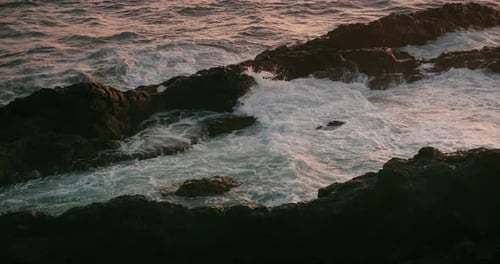 Ocean Waves Breaking on Rocky Beach at Warm Sunset Light Closeup Raging Stormy Sea Foam Water