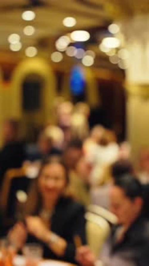 Blurred Adults Gather at Tables in Banquet Hall