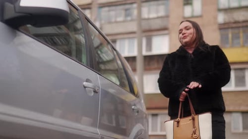 Woman Approaches Vehicle Opens Door to Enter Car Parked on Urban Street in Eastern Europe Commuter