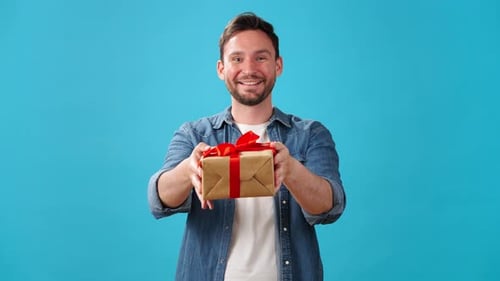Smiling Man Holding Out Birthday Present in Studio