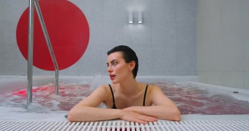 Charming Brunette Lady Taking Warm Bath In SPA Center Enjoying Jacuzzi And Pool Hydrotherapy