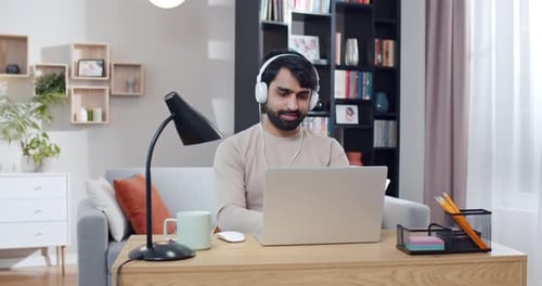 Man Working on Laptop at Home with Headphones