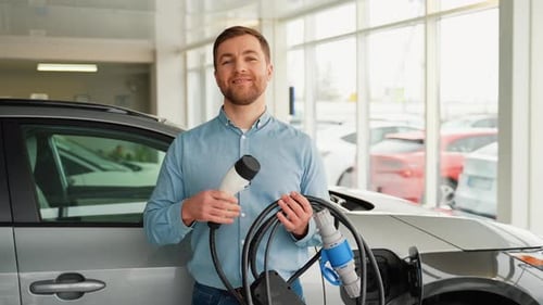 Man Holding Charger at Electric Car Dealership