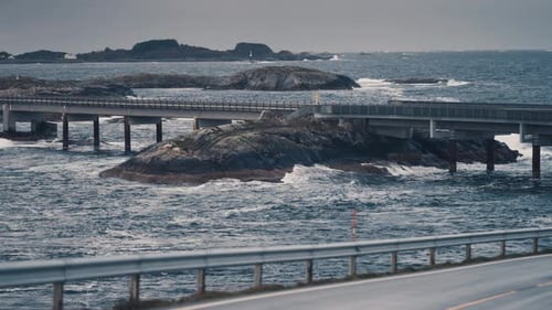 Famous Atlantic ocean road winding through the rocky archipelago. Powerful waves crash on the rocks