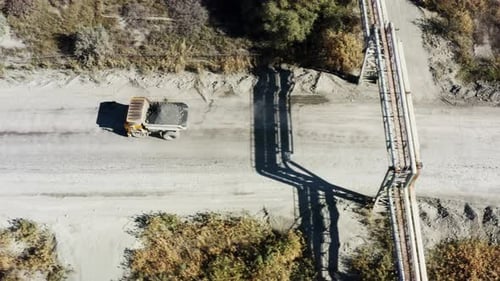 An Aerial View of Various Industrial Equipment Positioned on a Graveled Road Surrounded By Nature