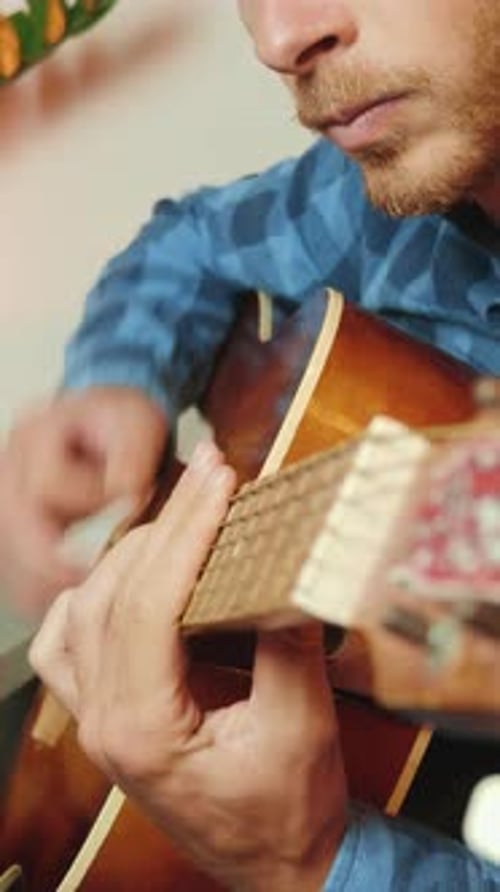 Mann spielt im Tonstudio auf Gitarrensaiten. Vertikales Video