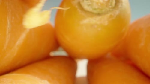 raw fresh carrots on a white table, the camera passes under the carrot. Dolly slider extreme close-u