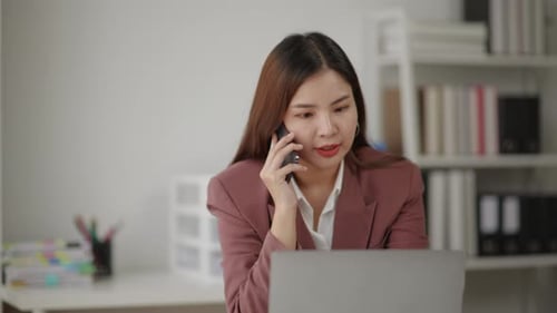Woman Talks on Phone While Working on Laptop