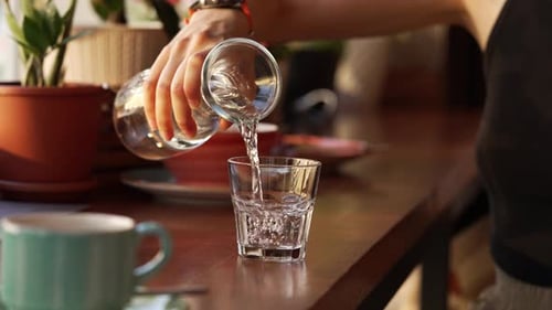 Woman Pours Water from Carafe Into Glass