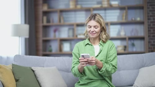 Woman Using Smartphone on Sofa at Home