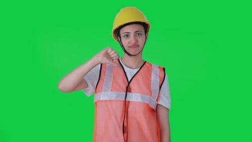 Upset Indian female construction worker showing thumbs down Green screen