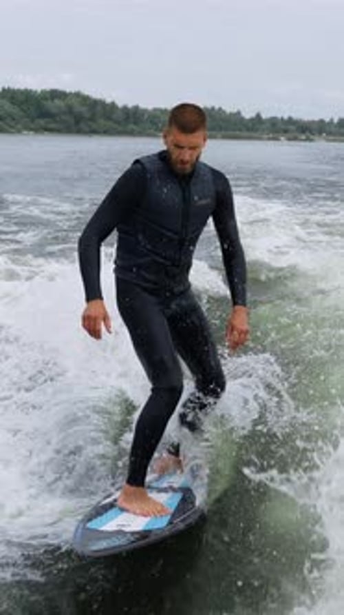 A Surfer Riding the Wake Captured Moments of Thrilling Water Sports Action on a Surfboard As He
