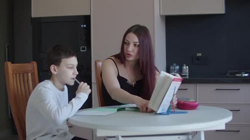 Woman and Boy Studying Together at Kitchen Table