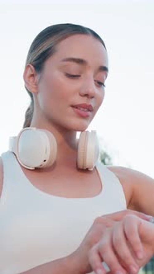 Young Female Runner Looks at Smartwatch Device Fitness Bracelet Heart Rate Pulse SPO2 in City Park