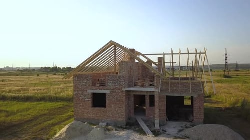 Aerial View of Unfinished Brick House with Wooden Roof Structure Under Construction