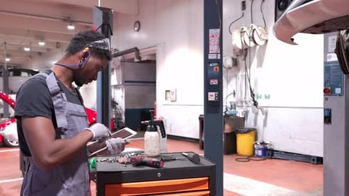 Car Mechanic Inspecting Vehicle with Tablet in Repair Shop