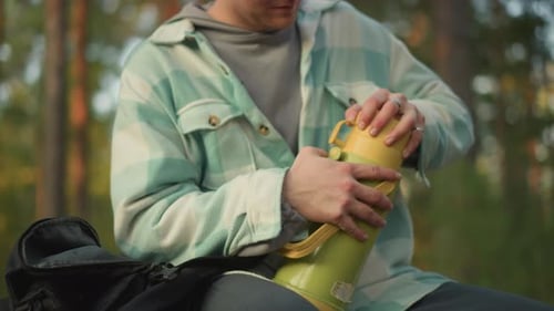 White Hiker Unzips Backpack Pulls Thermos in Quiet Pine Forest Morning Hands Steady Unscrewing Lid