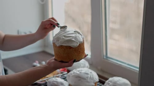 Caucasian Woman decoretes freshly cooked Easter Cakes. Cooking homemade traditional Easter Cakes