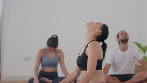 Group Yoga Class in a Bright Studio with Instructor Giving Guidance